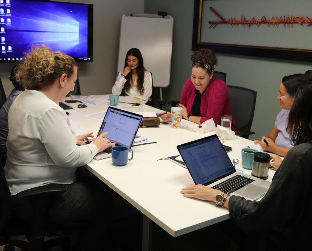 Co-workers convene for a team meeting around a conference room table